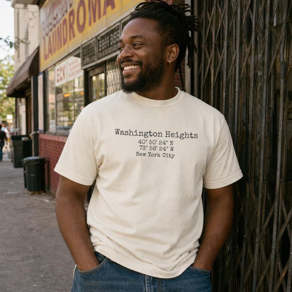 Man wearing an Ivory Comfort Colors t-shirt with 'Washington Heights' coordinates, standing on a street.