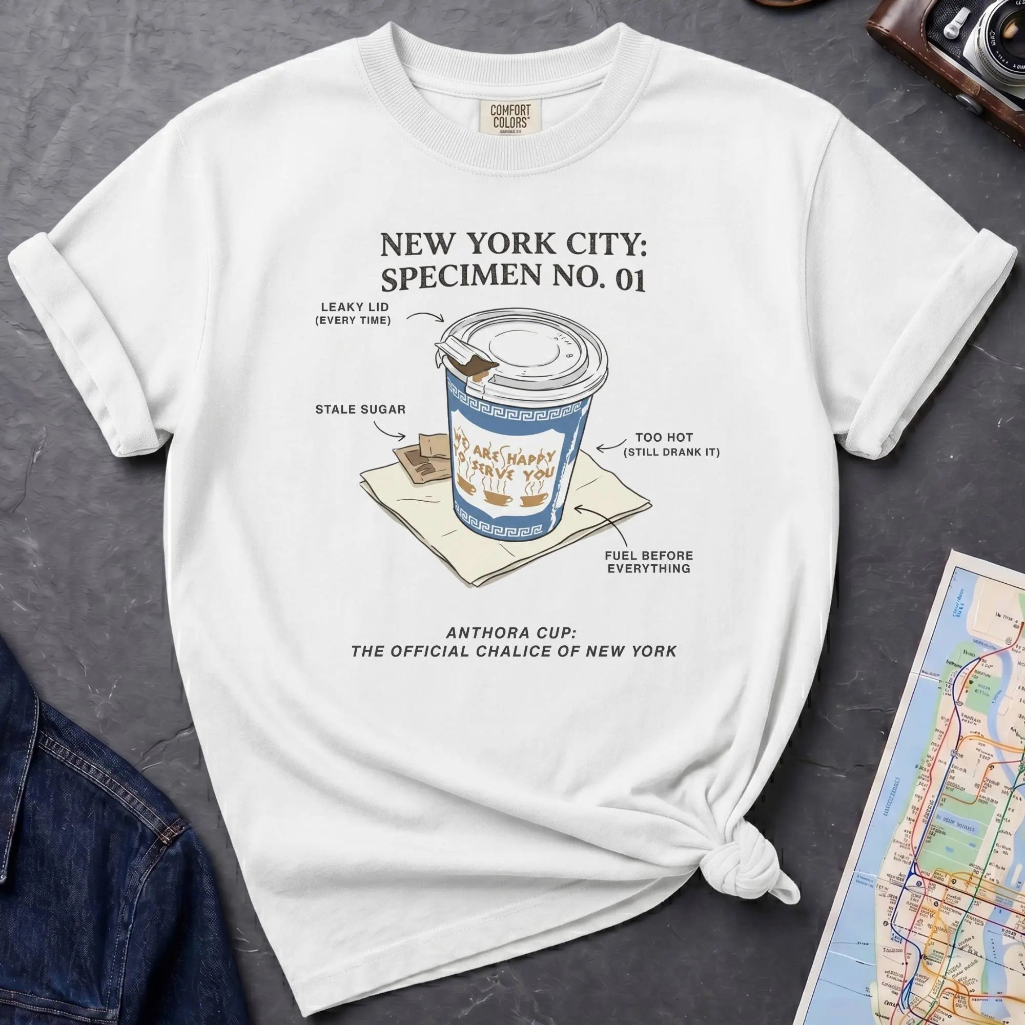 White Comfort Colors t-shirt featuring a vintage New York City Anthora coffee cup graphic with specimen-style callouts and “The Official Chalice of New York” text.
