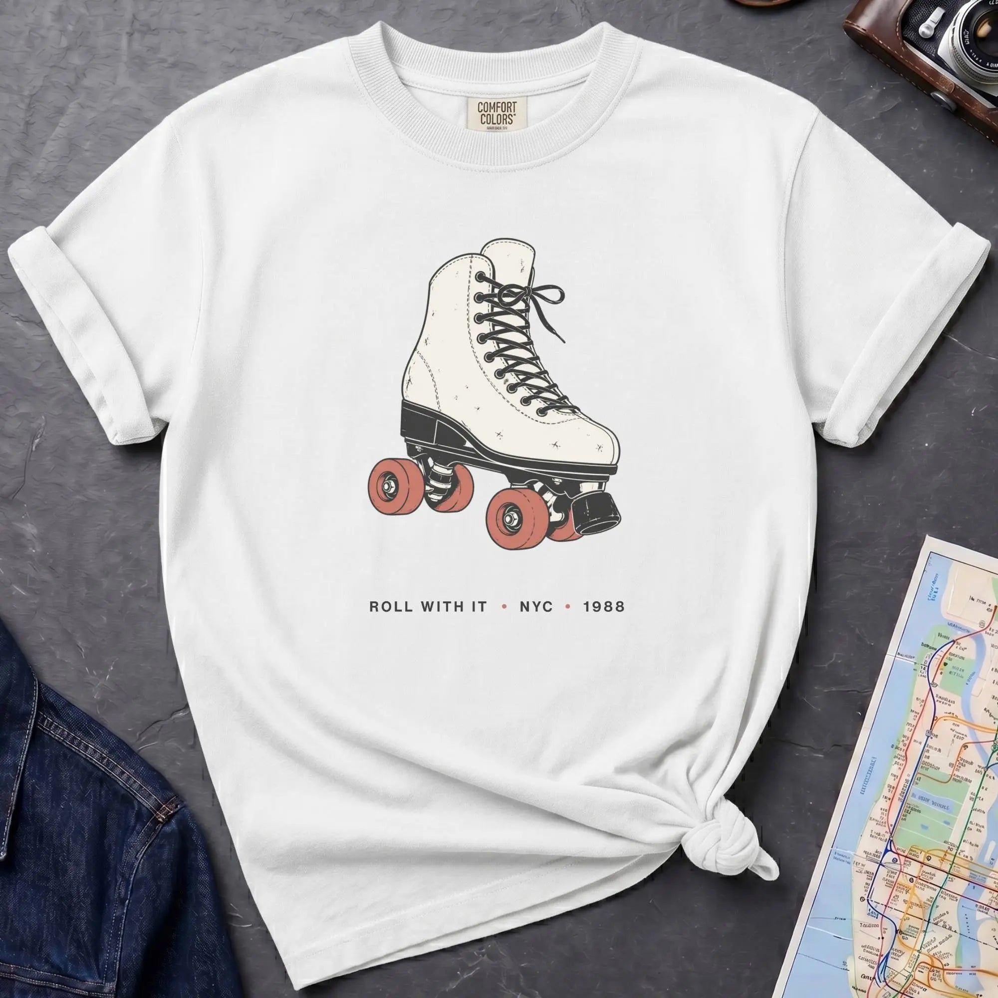 White Comfort Colors t-shirt featuring a vintage roller skate graphic with “Roll With It • NYC • 1988” text.