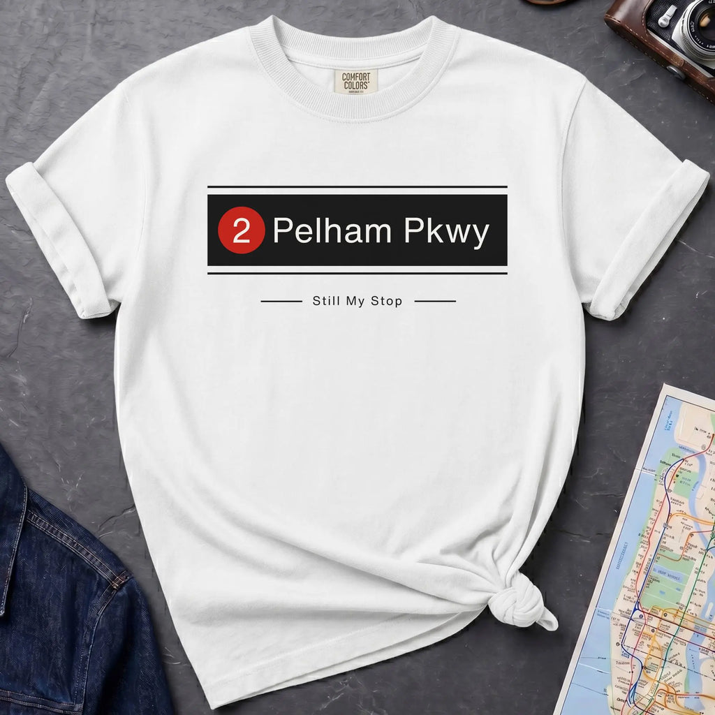 White t-shirt with 'Pelham Pkwy' design on a gray surface with a map and jeans.