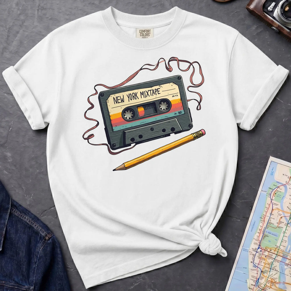 White t-shirt with a cassette tape graphic and pencil on a gray surface with a map and denim jacket.