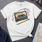White t-shirt with a cassette tape graphic and pencil on a gray surface with a map and denim jacket.