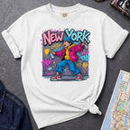 White Comfort Colors t-shirt featuring a colorful NYC graffiti-style New York graphic with a young street artist holding a spray paint can