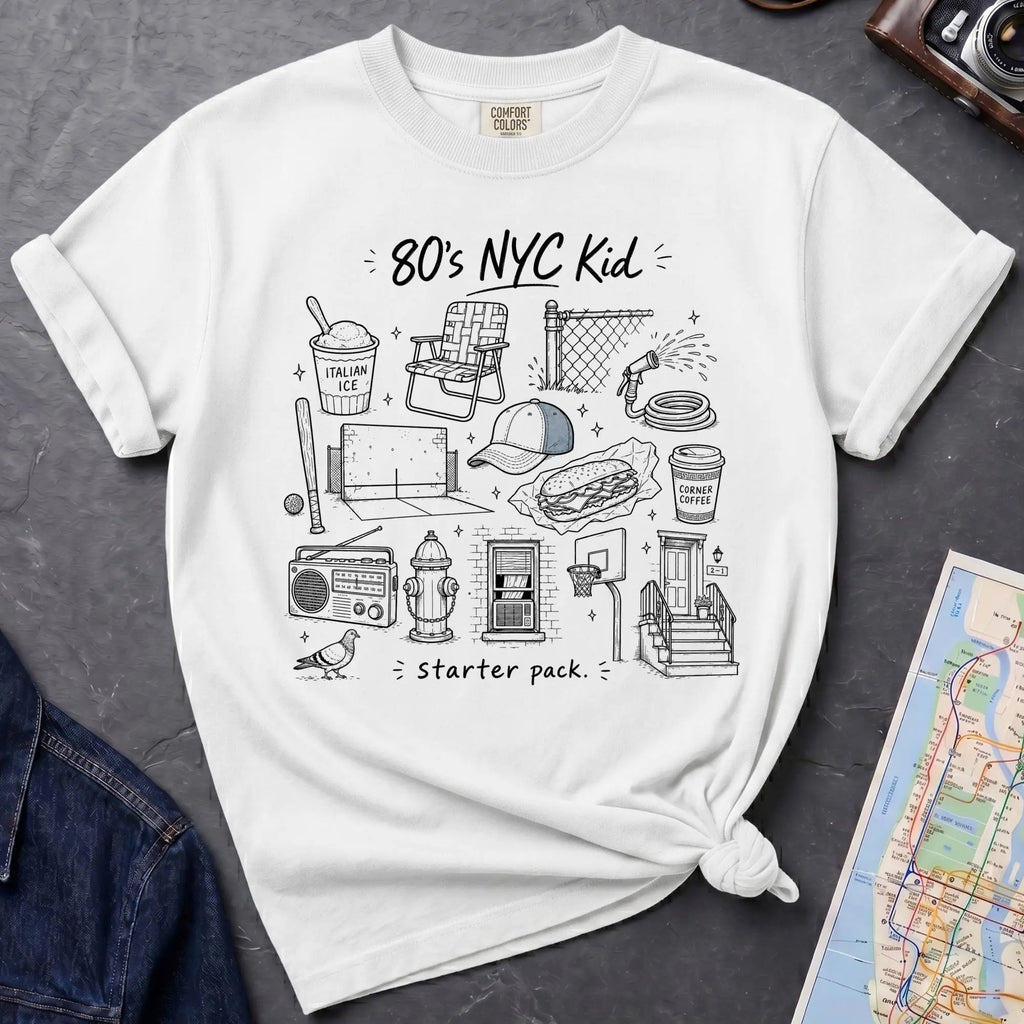 White Comfort Colors t-shirt featuring an 80’s NYC Kid Starter Pack graphic with hand-drawn New York City icons including Italian ice, a radio, stoop steps, stickball, a fire hydrant, and a pigeon.
