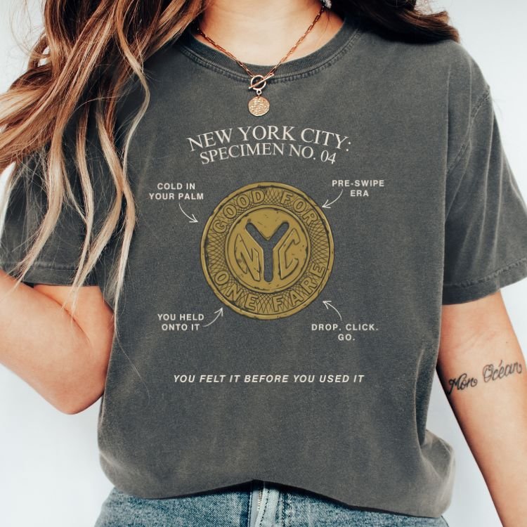 Pepper-colored t-shirt with a vintage specimen diagram of a gold NYC subway token labeled Specimen No. 04 in white type