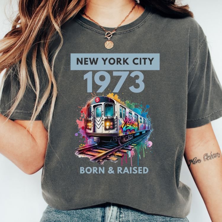Custom NYC subway graffiti birth year tee with Born & Raised text on a pepper-colored shirt.