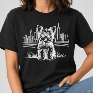 Black t-shirt with a white line art Yorkshire terrier sitting in grass in front of the NYC skyline and Empire State Building.