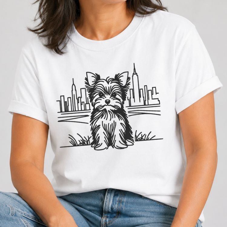 White t-shirt with a white line art Yorkshire terrier sitting in grass in front of the NYC skyline and Empire State Building.